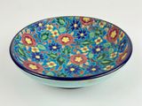 blue and red bowl with floral design on it on a white surface