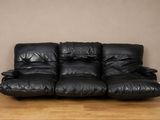 un canapé en cuir noir posé sur un parquet en bois massif