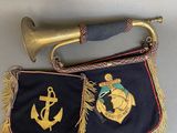 an old brass trumpet and an old navy flag hanging on a wall