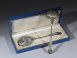 une cuillère en argent et un repose-cuillère dans une boîte bleue