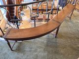 a curved wooden bench in the middle of a room