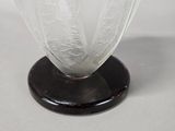 a glass vase with a black base on a white table