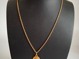 un collier en or avec une pièce de monnaie sur le cou d'un mannequin