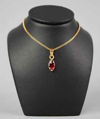 un collier plaqué or avec un pendentif en pierre rouge sur un mannequin noir