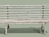 un banc en bois blanc dont l'ombre se projette sur le sol