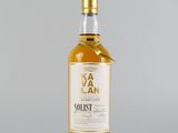 une bouteille de whisky posée sur une surface blanche, avec un fond gris