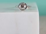 a close up of a diamond ring sitting on top of a white marble block