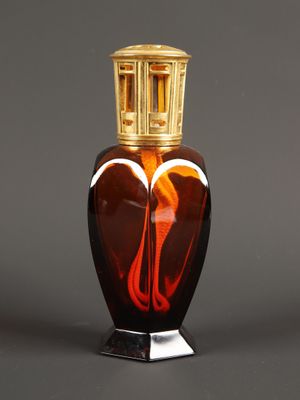 une image représentant un vase en verre orné d'un couvercle doré