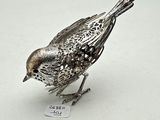 a silver bird that is sitting on a white surface