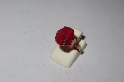 a ring with a red stone on it on a white surface