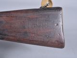 someone is holding a rifle with a wooden handle on a gray surface