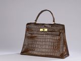 a close up of a brown alligator skin handbag on a white surface
