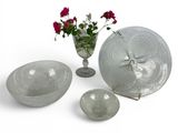 a glass bowl, plate, and vase with flowers in it