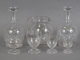 three clear glass vases and a pitcher on a gray surface
