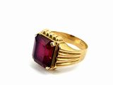 a close up of a gold ring with a red stone
