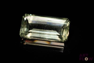 un gros plan d'une tourmaline verte posée sur une surface noire
