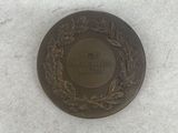 a bronze medal with a wreath on it on a white surface