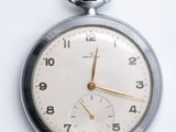 une montre de poche en argent posée sur une surface blanche