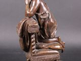 bronze statue of a woman sitting on a chair with her hands on her head