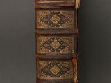 an old book sitting on top of a table next to a black wall