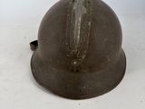 an old helmet sitting on top of a table next to a white wall
