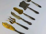 a lot of different types of knives and spoons on the table