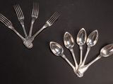 several spoons and forks are arranged on a black surface