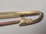 a close up of a gold pin with a arrow on it