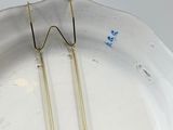 a white plate with a pair of gold earrings on it