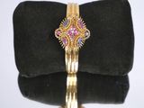 an image of a gold bracelet with pink and blue stones on it