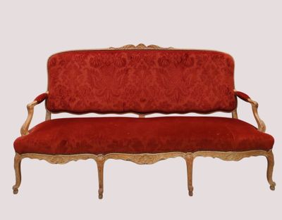 une image représentant un canapé rouge avec une structure dorée et des coussins rembourrés rouges