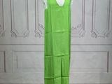 green dress on a mannequin stand in front of a white wall
