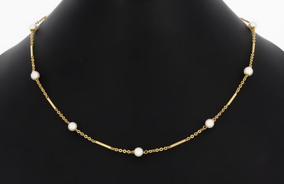 a gold necklace with pearls on a mannequin mannequin
