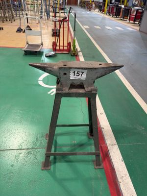 a metal anvil on a green floor in a warehouse
