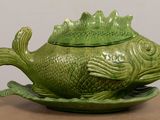 a green fish shaped dish with a lid on a table