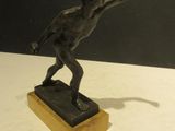 bronze statue of a boy throwing a frisbee on a wooden base
