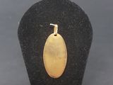 a close up of a gold plated pendant on a black display case