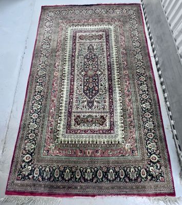 Un tapis oriental est posé sur le sol, à côté d'un lit de bébé.