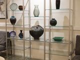 a glass display case with vases on it in the corner of a room
