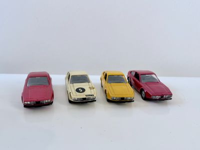 quatre petites voitures sont alignées sur une surface blanche