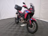 une moto rouge et bleue garée sur un sol à damier noir et blanc