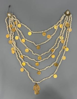un collier composé de pièces d'or et de perles, présenté sur un mannequin