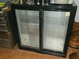 a glass door refrigerator sitting in a kitchen next to a counter
