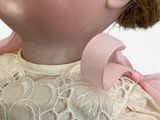 a close up of a doll with a pink bow on it ' s head