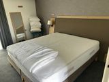 a bed with a white comforter and a mirror in the corner