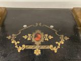 a black and gold table with a red stone in it