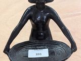 une statue représentant une femme tenant un bol posé sur une table
