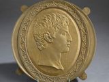 gold plate with a portrait of a woman in profile on a stand