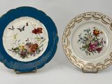 two plates with flowers and butterflies on them sitting next to each other