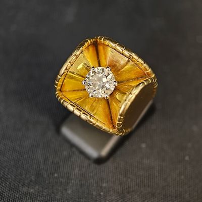 une bague jaune sertie d'un diamant, posée sur un fond noir